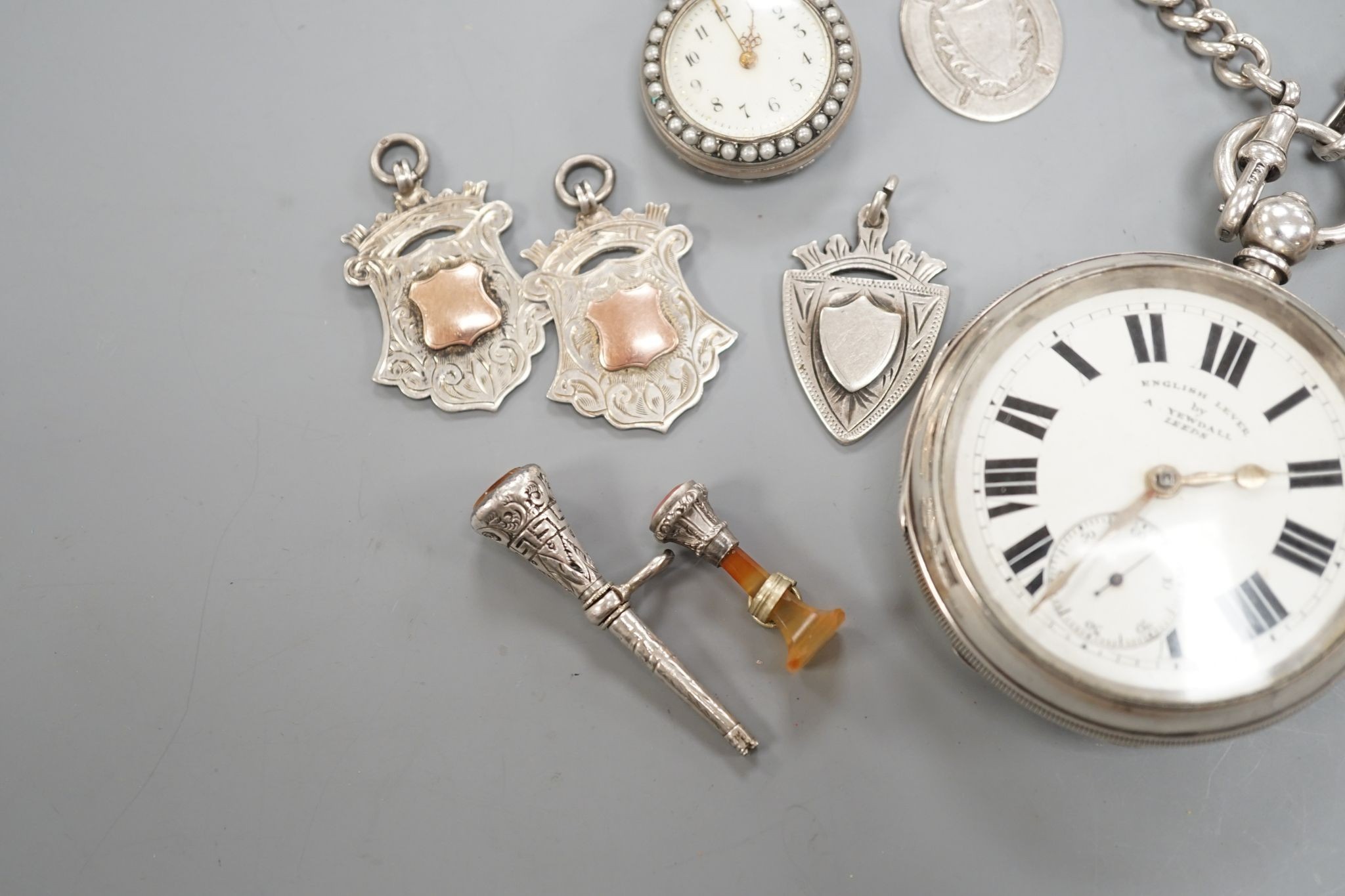 A George V silver open faced lever pocket watch, by A. Yewdall, Leeds, on a silver albert hung with silver medallions, two Swiss white metal and enamel fob watches, gilt fob seal, etc.
